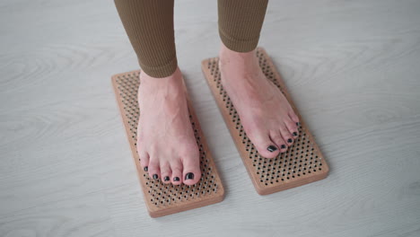 high angle yogi standing barefoot on wooden nail mat in bright studio focusing on balance wellness grounding under soft ambient light reflecting mindful presence energy and strength