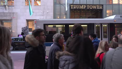 two protesters outside of trump tower in manhattan, people walking by during christmas holiday time