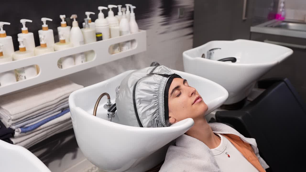 Giovane donna che riceve un trattamento di vaporizzazione dei capelli in un salone moderno