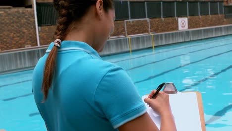 female swim coach writing on clipboard