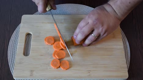 man's hand cutting a carrot.top view