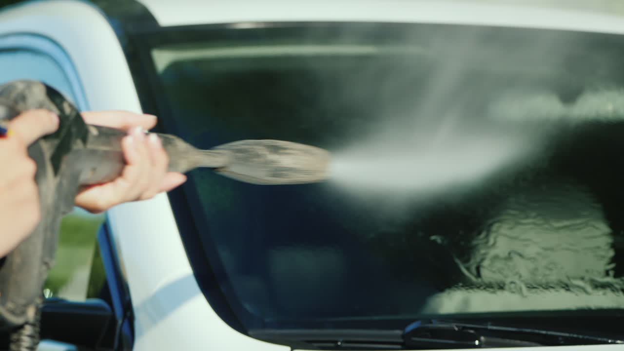 고압세척기로 자동차 앞유리의 먼지를 씻어냅니다.