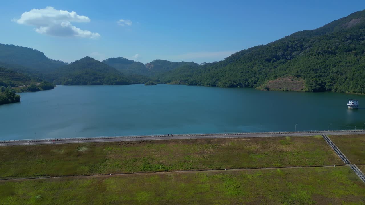 Vista aérea de una gran presa y embalse rodeados de montañas verdes.