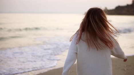 portraitof a blonde woman looks to the camera, relaxfuly walks along the seashore