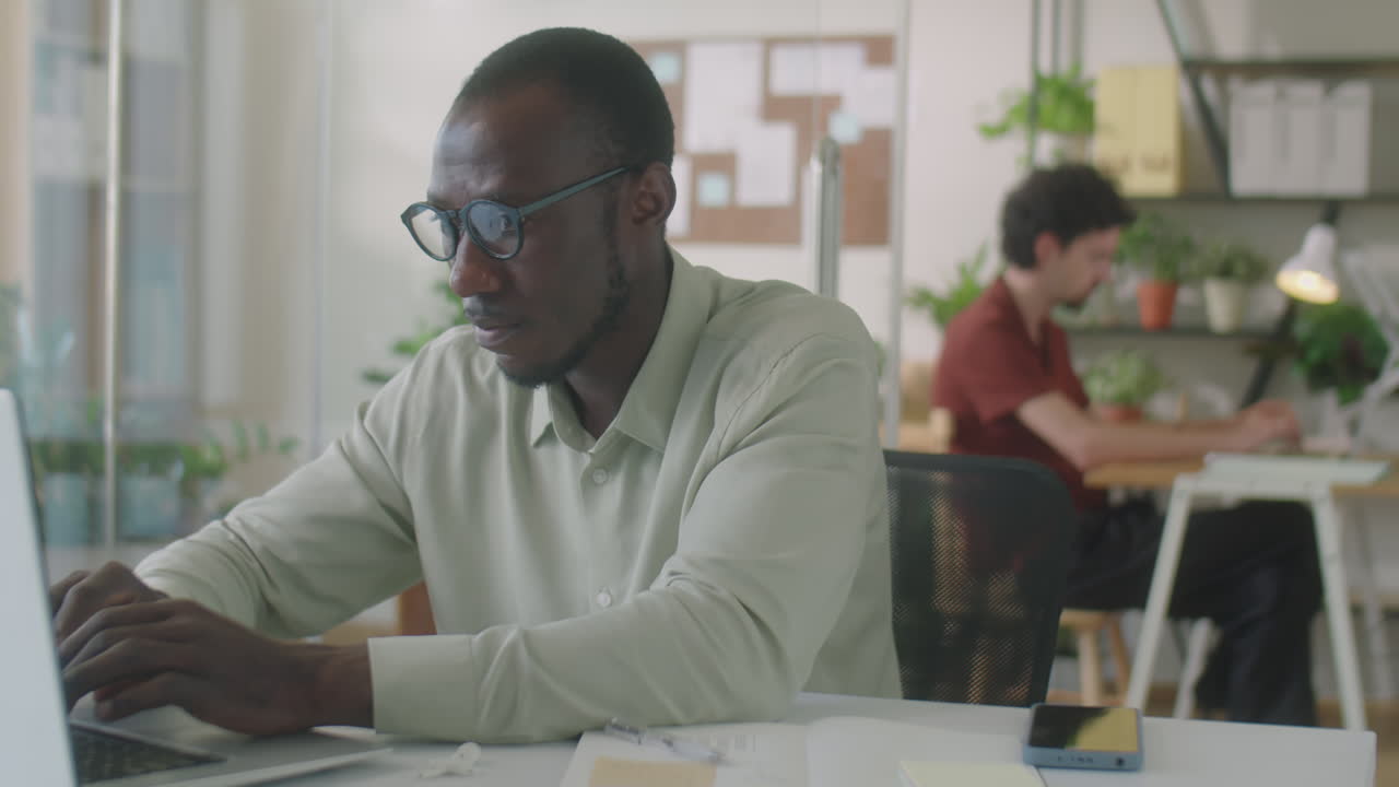 African American Office Worker Using Laptop at Desk