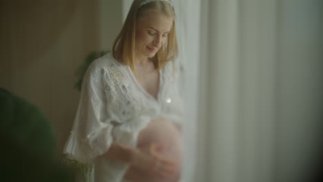 smiling pregnant woman by a window