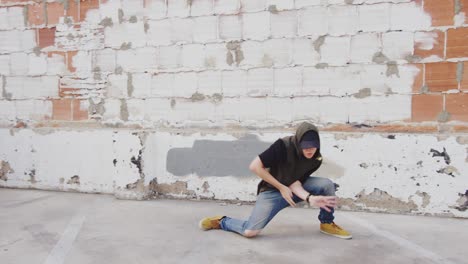 man hip hop dancing outside in city in front of brick wall