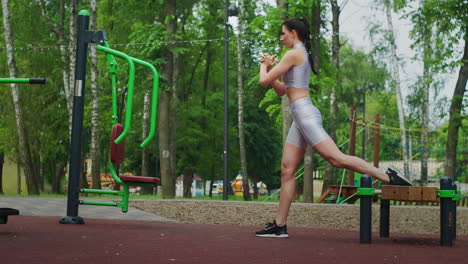 una mujer joven en un parque realiza sentadillas en una pierna en un banco en ropa deportiva en el verano. atletismo mujer caucásica entrena en el parque
