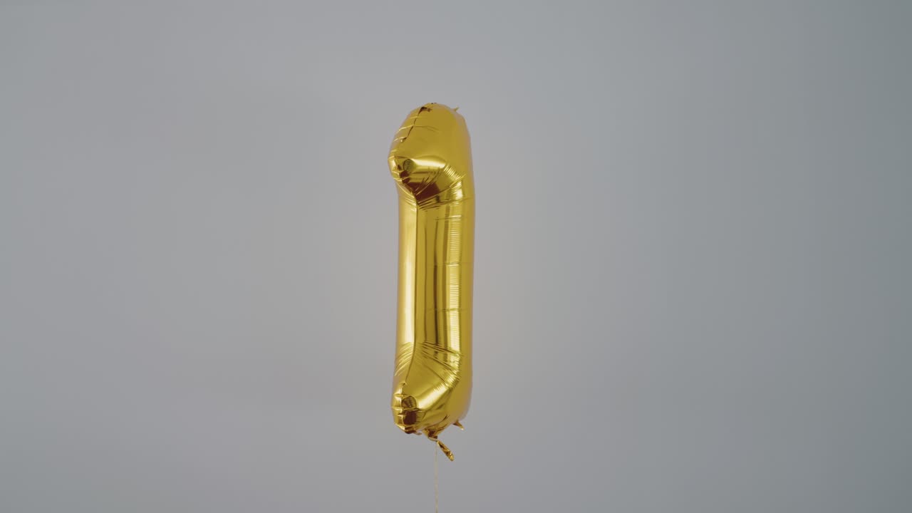golden number one balloon drifting calmly in minimalist grey space