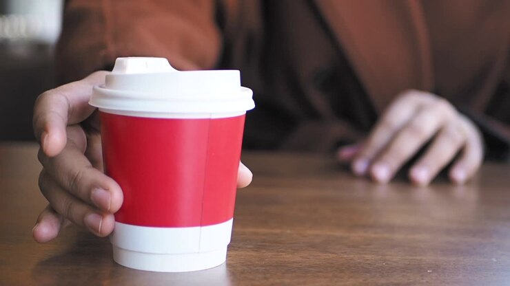 Person holding a red coffee cup