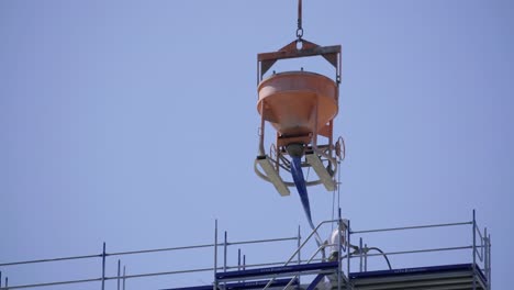 Concrete bucket lifted by crane at construction site