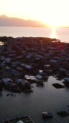 populated bungin island with pile dwellings at sunset in indonesia. - aerial vertical shot
