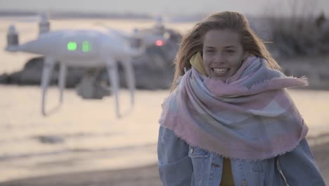 mujer divertida haciendo video en la playa usando un dron