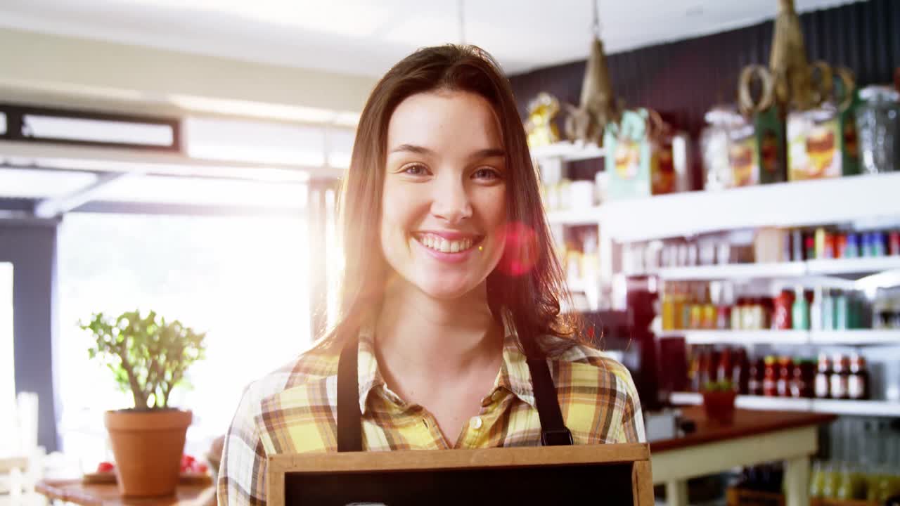 camarera sonriente mostrando la pizarra con un letrero abierto