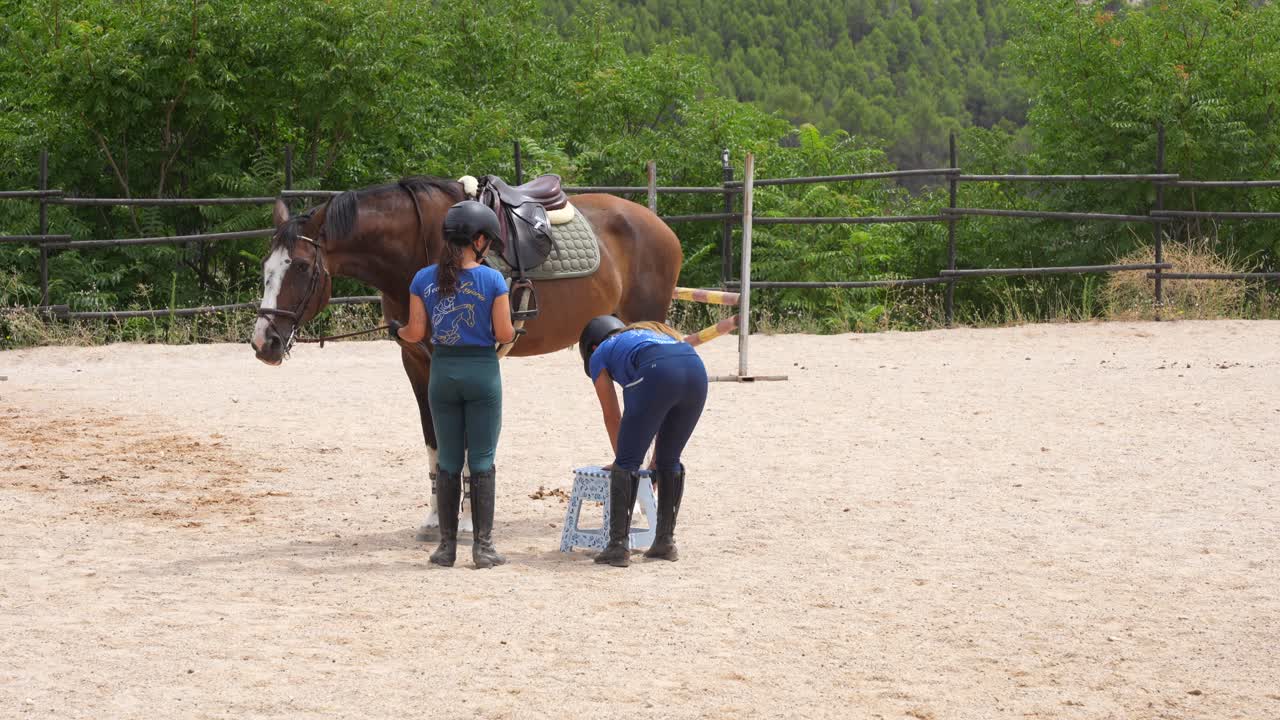 Rider asks a mate for a mounting stool while other gallops around the track on pony, 4K