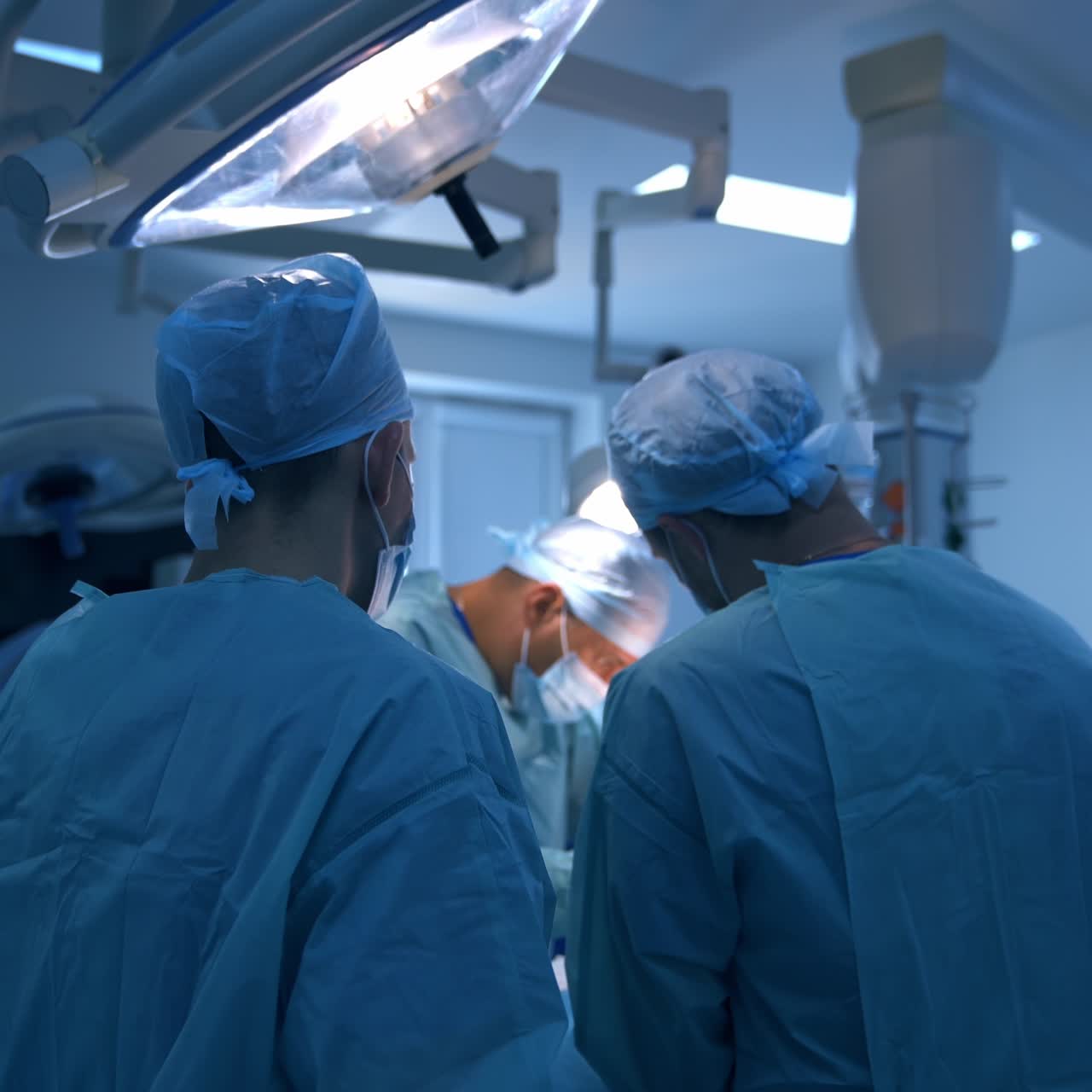 To mandlige læger, der assisterer kirurgen under en operation. Et professionelt team udfører plastikkirurgi på en innovativ klinik.