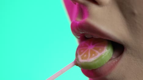 young woman eating a kiwi popsicle lollypop, candy snack in close-up, green background