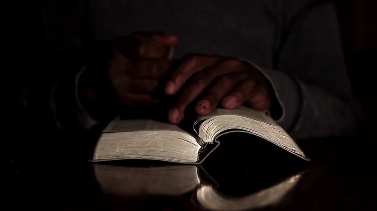 praying to god with hands together with bible and cross Caribbean man praying with black background stock video