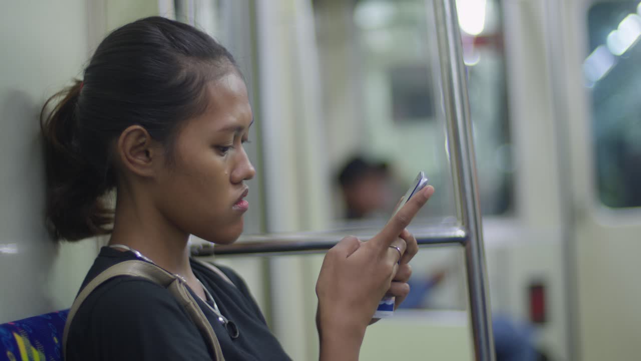Woman using mobile phone on subway train