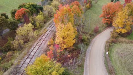 Schwenken-Der-Herbstdrohnenansicht-Der-Bahnstrecke-Und-Der-Unbefestigten-Straße