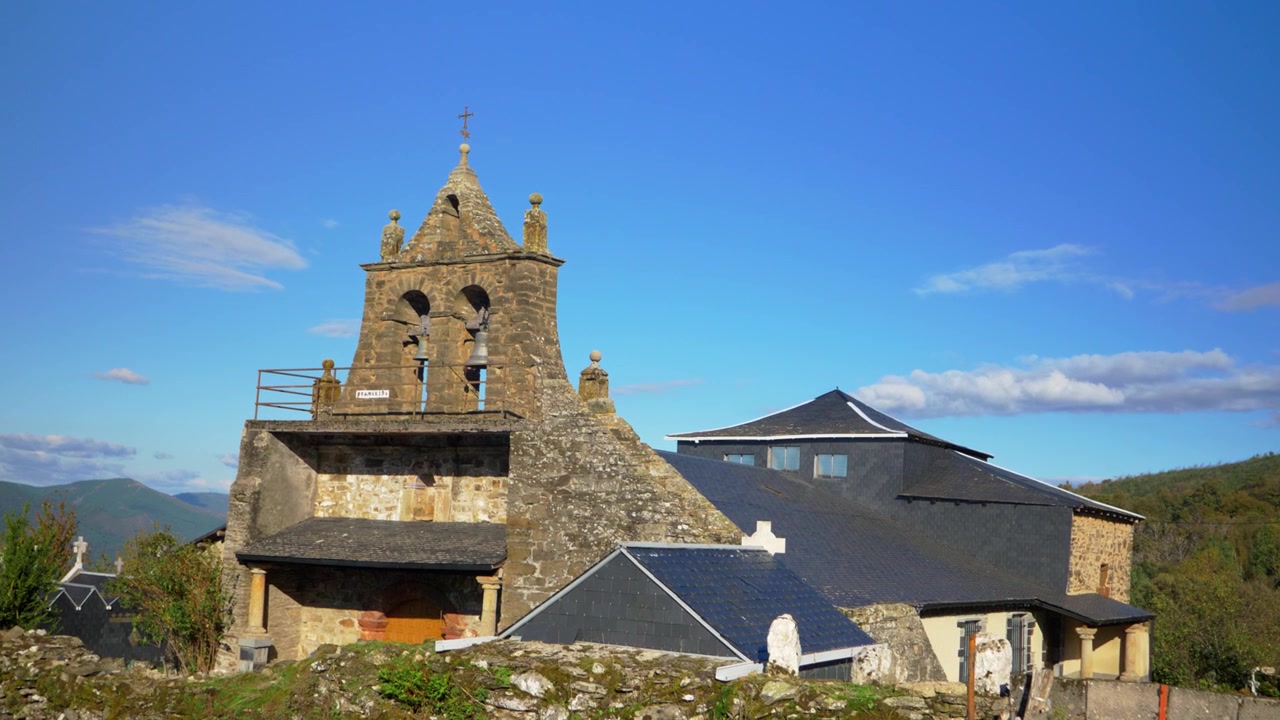 Vista esterna della chiesa parrocchiale di Santa Mariña do Monte, con il suo campanile in pietra, i tetti in ardesia e l'ambiente montano rurale vicino a O Barco de Valdeorras in Galizia, Spagna nord-occidentale