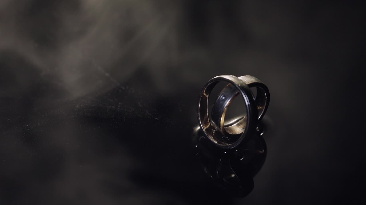 Wedding rings on dark water surface shining with light. Close up macro