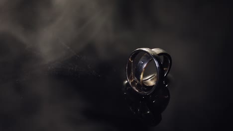 anillos de bodas en la superficie del agua oscura brillando con la luz. macro de primer plano