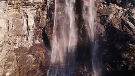 aerial drone footage pushing in at an impressive waterfall with colorful light reflections in grindelwald in switzerland