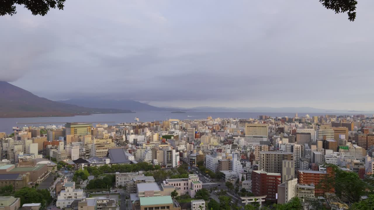Slow motion panoramic panning shot over Kagoshima cityscape with Sakurajima in distance