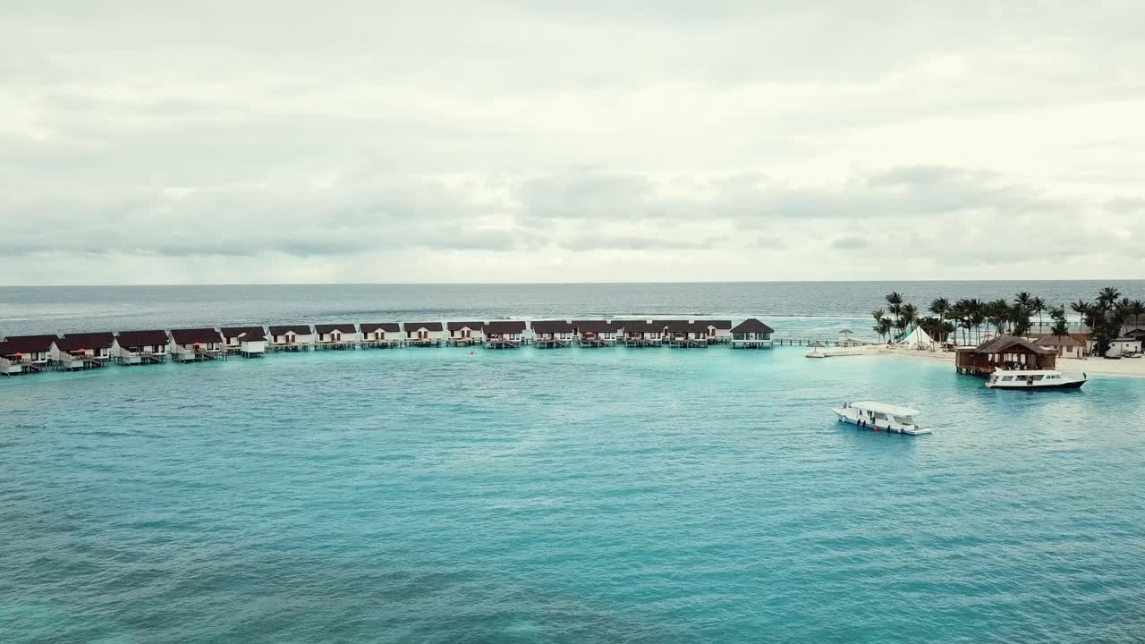 video de avión no tripulado de un complejo tropical en las maldivas, arrecife de la laguna azul, tiempo soleado, aguas poco profundas turquesa, villas acuáticas, puerto de la isla, 4k