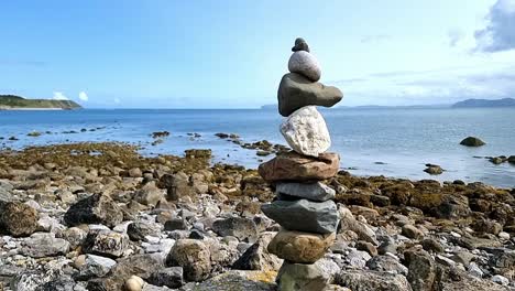 pila equilibrada de piedras de la torre zen en el horizonte de la playa de verano cielo azul soleado