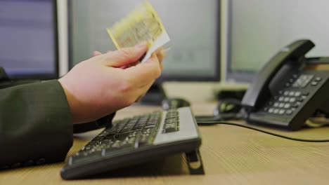 un hombre de negocios con dinero de euro roto en sus manos está trabajando en un teclado de computadora en un escritorio de oficina, primer plano