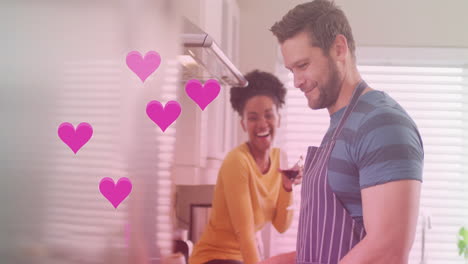 animation of hearts over diverse couple cooking together and drinking wine in kitchen at home