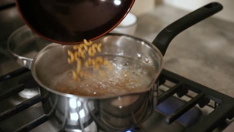 verter pasta seca en una olla de agua hirviendo a cámara lenta