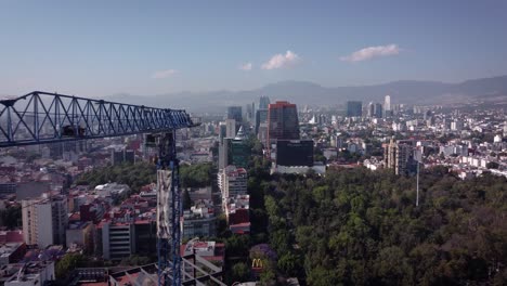 Grúa-Torre-Azul-En-Construcción-De-Vigas-De-Acero-En-Progreso-Ubicada-En-La-Avenida-Insurgentes-Cerca-Del-Parque-Hundido-Con-El-Sur-De-La-Ciudad-De-México-Al-Fondo