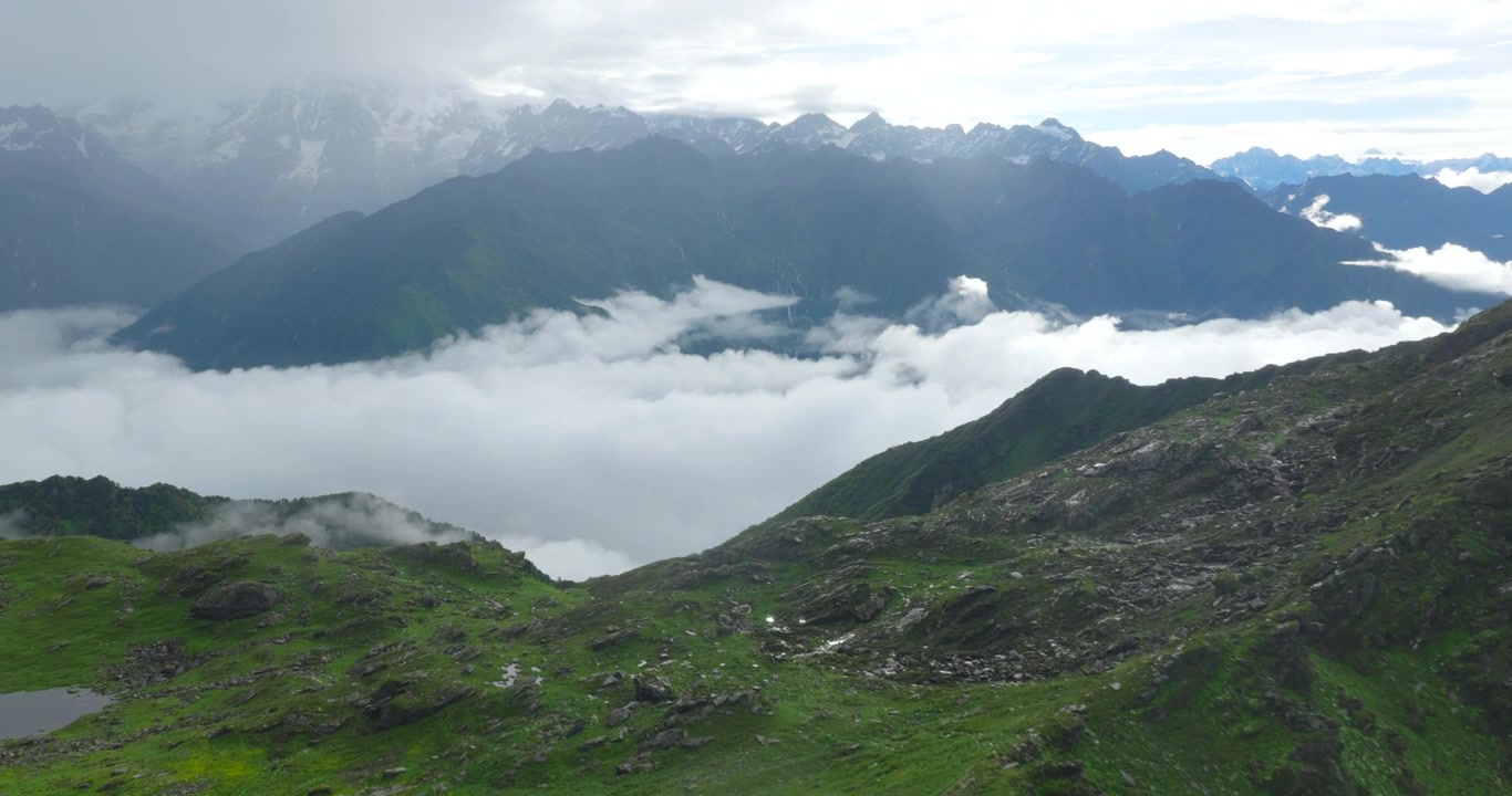 Drone revela inversão maciça de nuvens perto de uma crista verde e acidentada em primeiro plano, emoldurada por picos distantes do Himalaia com neve em Panchpokhari, Sindhupalchowk, Nepal
