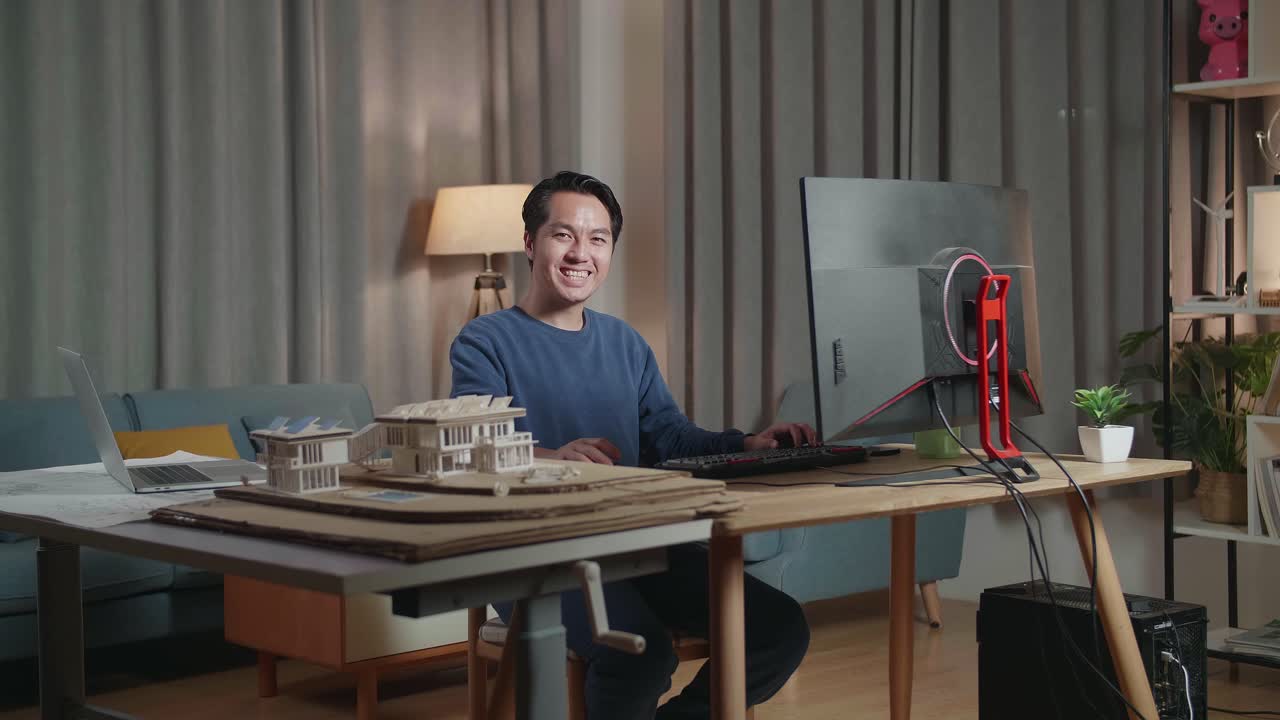 집에서 컴퓨터로 일하는 미소 짓는 남자