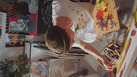 pintor masculino aplicando pintura al lienzo con un cuchillo de paleta