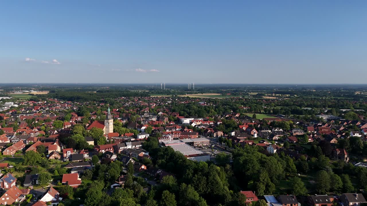 Quaint American townscape with red-brick rooftops, historic church tower and tree-lined streets. Classic suburban architecture in small-town of America under endless blue skies. Aerial wide shot