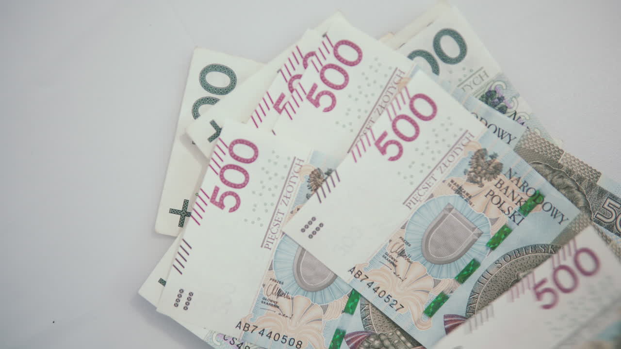 Mette 500 zloty polacchi su 100 zloty polacchi, contando i soldi a casa.