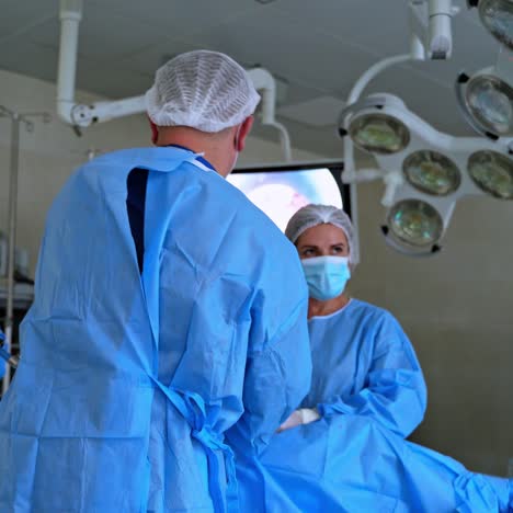 surgical procedure. group of doctors wearing medical uniform in operating room in hospital. healthcare workers perform operation looking on monitor.
