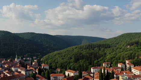 aerial view of a town nestled in a valley surrounded by mountains and forest