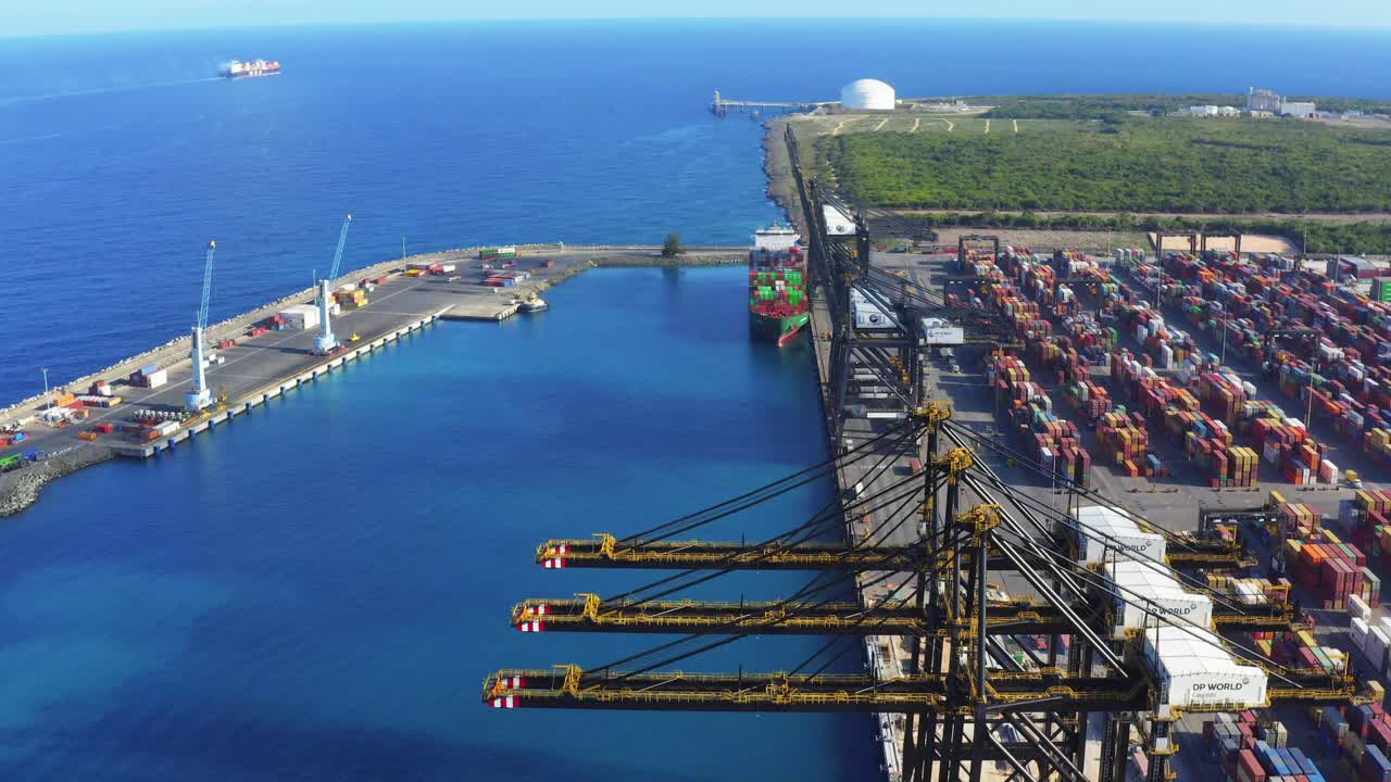 광대한 푸른 바닷물, 푼타 카우세도, 도미니카 공화국, 항공을 볼 수 있는 키 큰 크레인으로 조선소 터미널에 쌓인 다채로운 화물 컨테이너