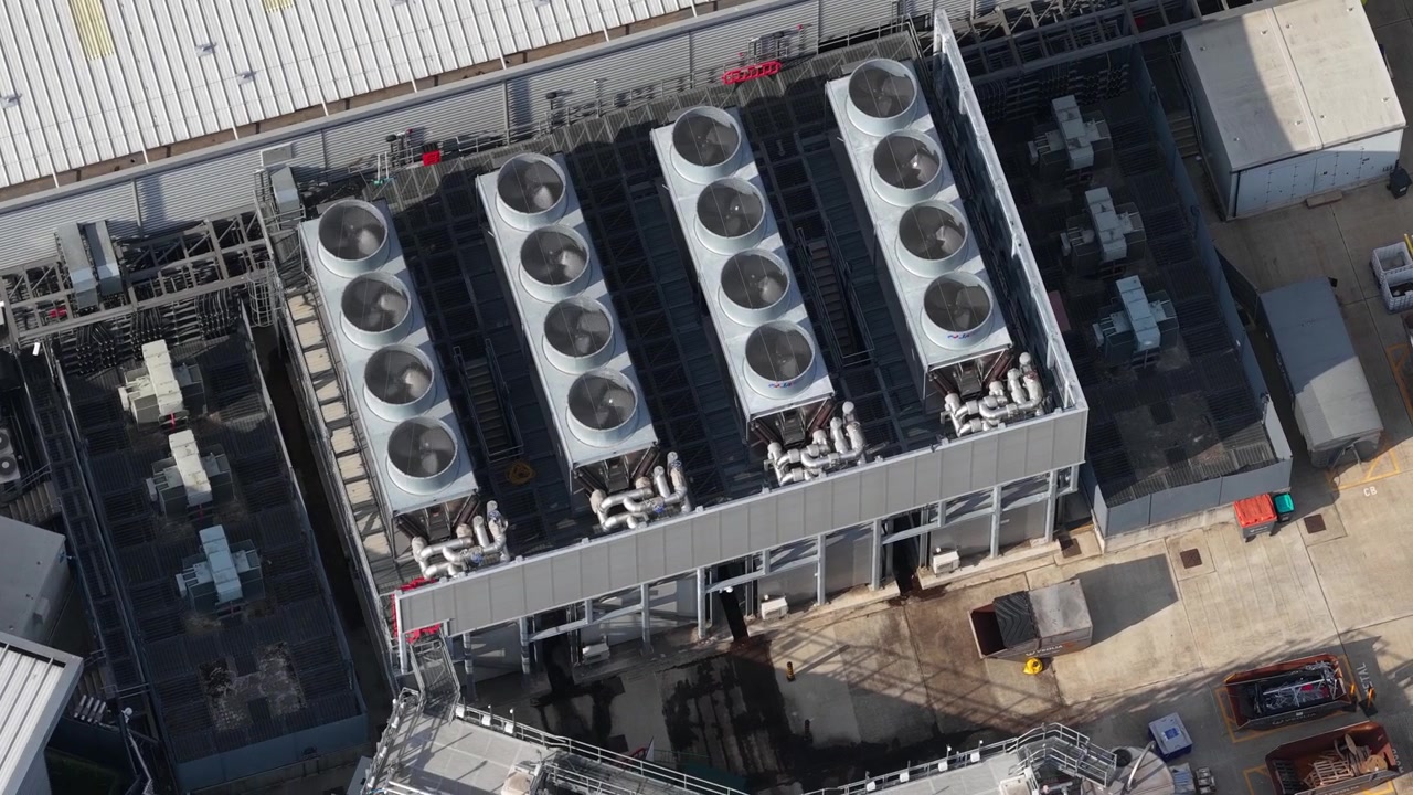 Aerial view of a large datacenter with its cooling system, featuring numerous fans on the roof maintaining the optimal temperature for servers processing big data and machine learning tasks
