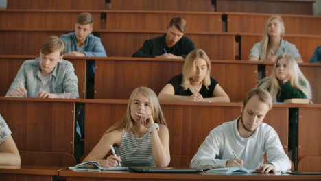 Im-Klassenzimmer-Hören-Multiethnische-Studenten-Einem-Dozenten-Zu-Und-Schreiben-In-Notizbücher.-Kluge-Junge-Leute-Studieren-Am-College.