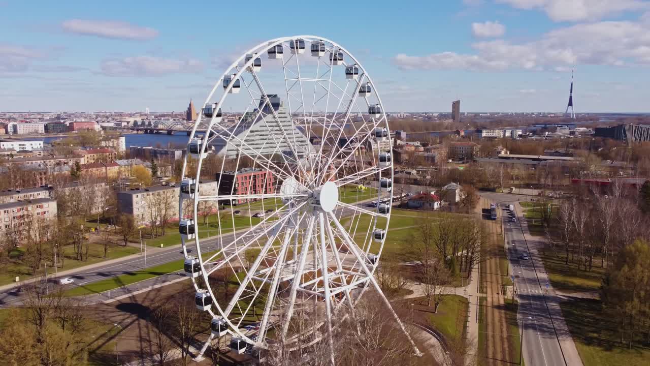 Modern Ferris wheel in Riga with city buildings and river in sunny spring view