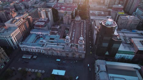 Vista-Aérea-Del-Amanecer-Dando-Vueltas-Sobre-Santiago,-Paisaje-Urbano-De-La-Iglesia-Católica-De-La-Catedral-Metropolitana