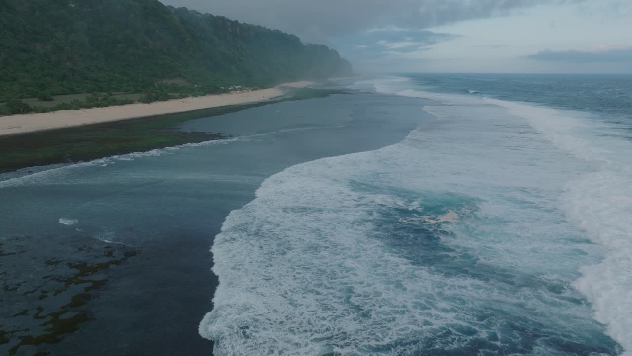 Slow Motion Drone of sunset wave action at low tide over coral and rock reef Nyang Nyang Beach, Bali, Uluwatu Indonesia