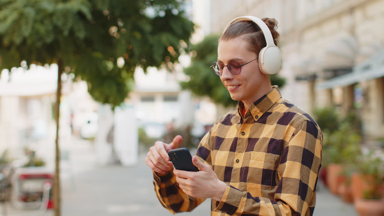 Man putting on wireless headphones choosing listening favorite energetic music on city street