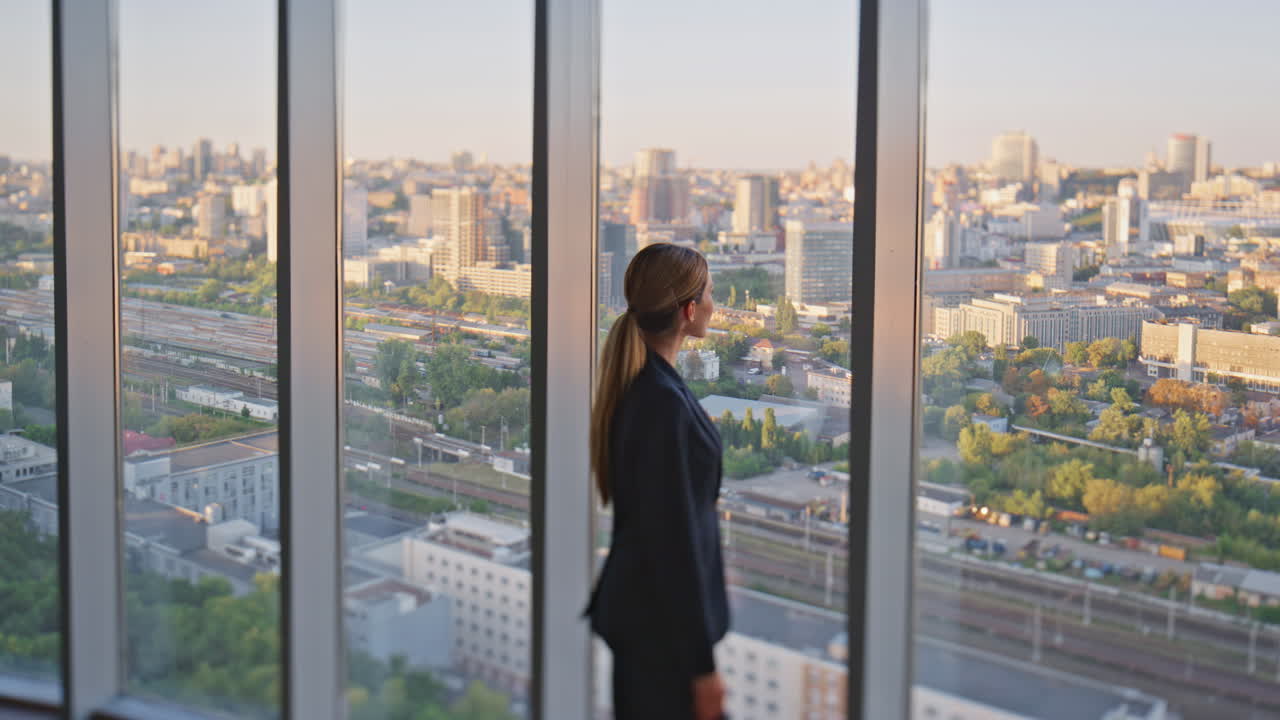 mujer líder pensando en el futuro mirando ventana panorámica en la oficina contemporánea.